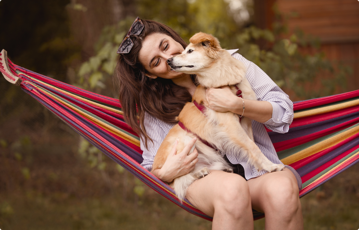 właścicielka z psem kundelkiem na kolorowym hamaku w letnich kolorach